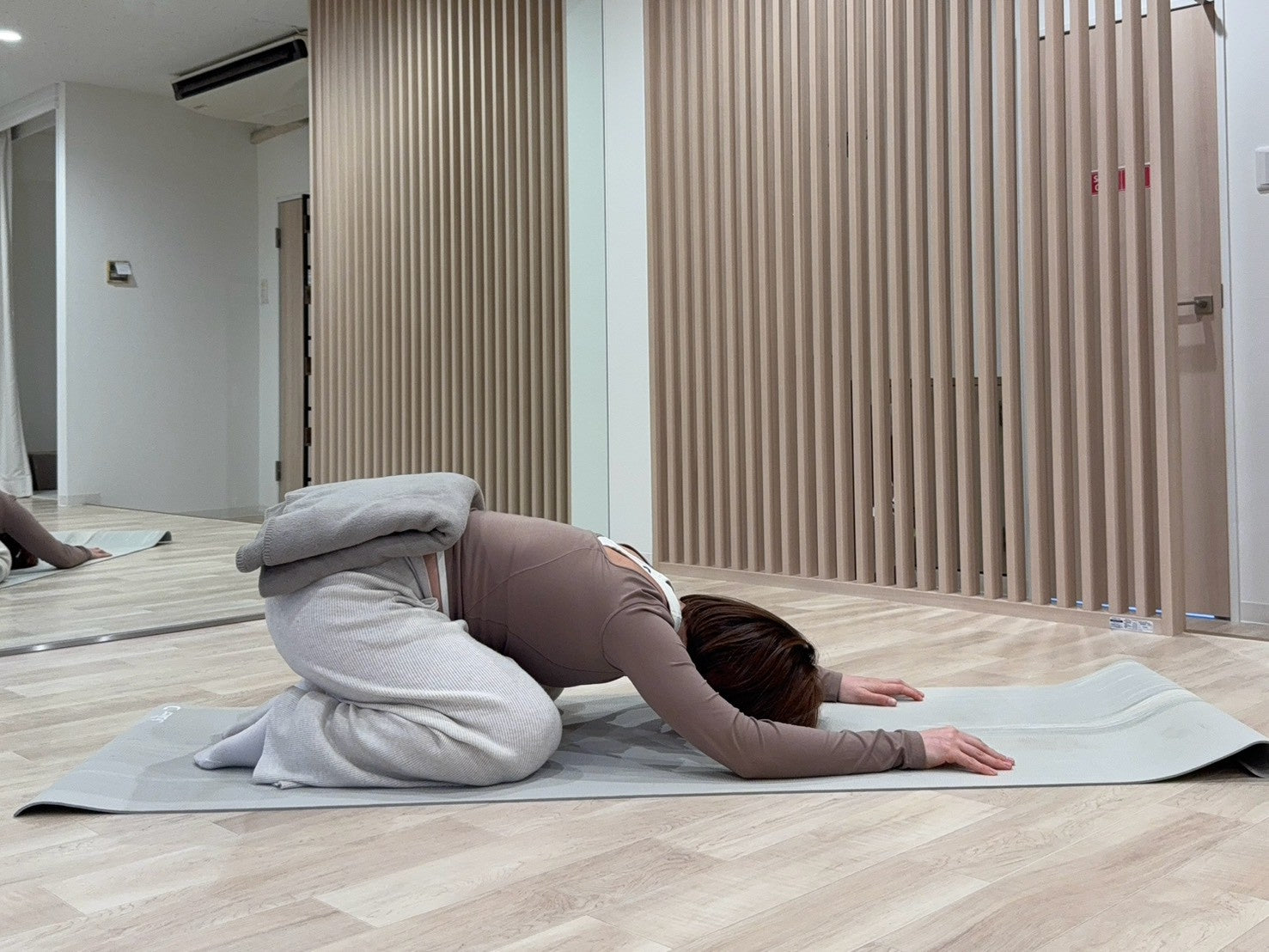 チャイルドポーズでヨガブランケットを腰にのせている写真