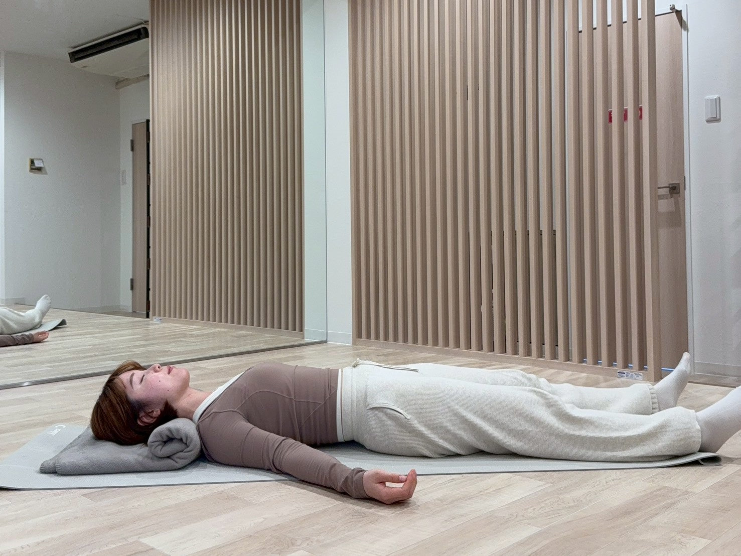 シャバーサナで首の下にヨガブランケットを丸めて入れている写真